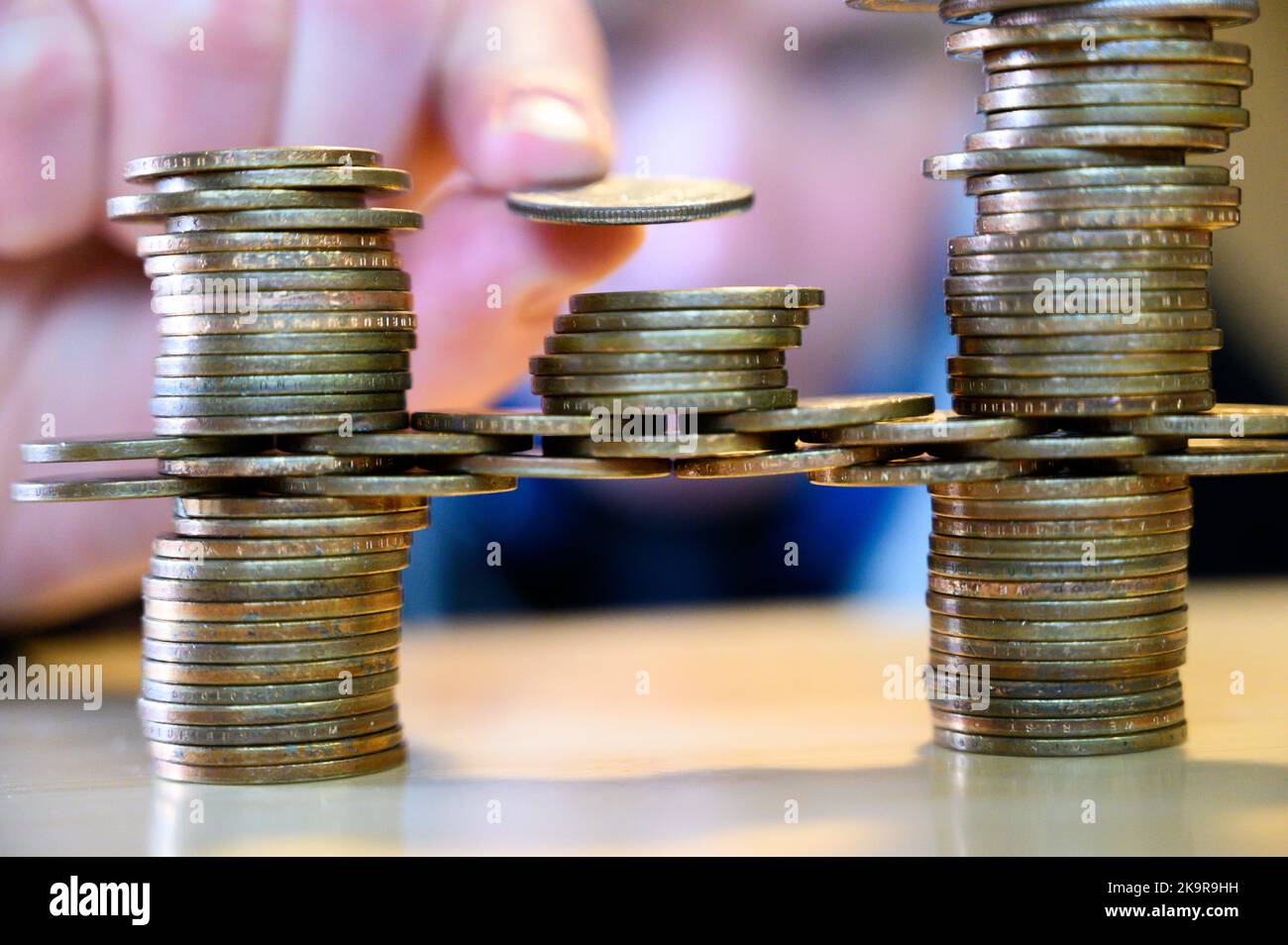 stacking gold dollar coins into bridge using a cantilever Stock Photo