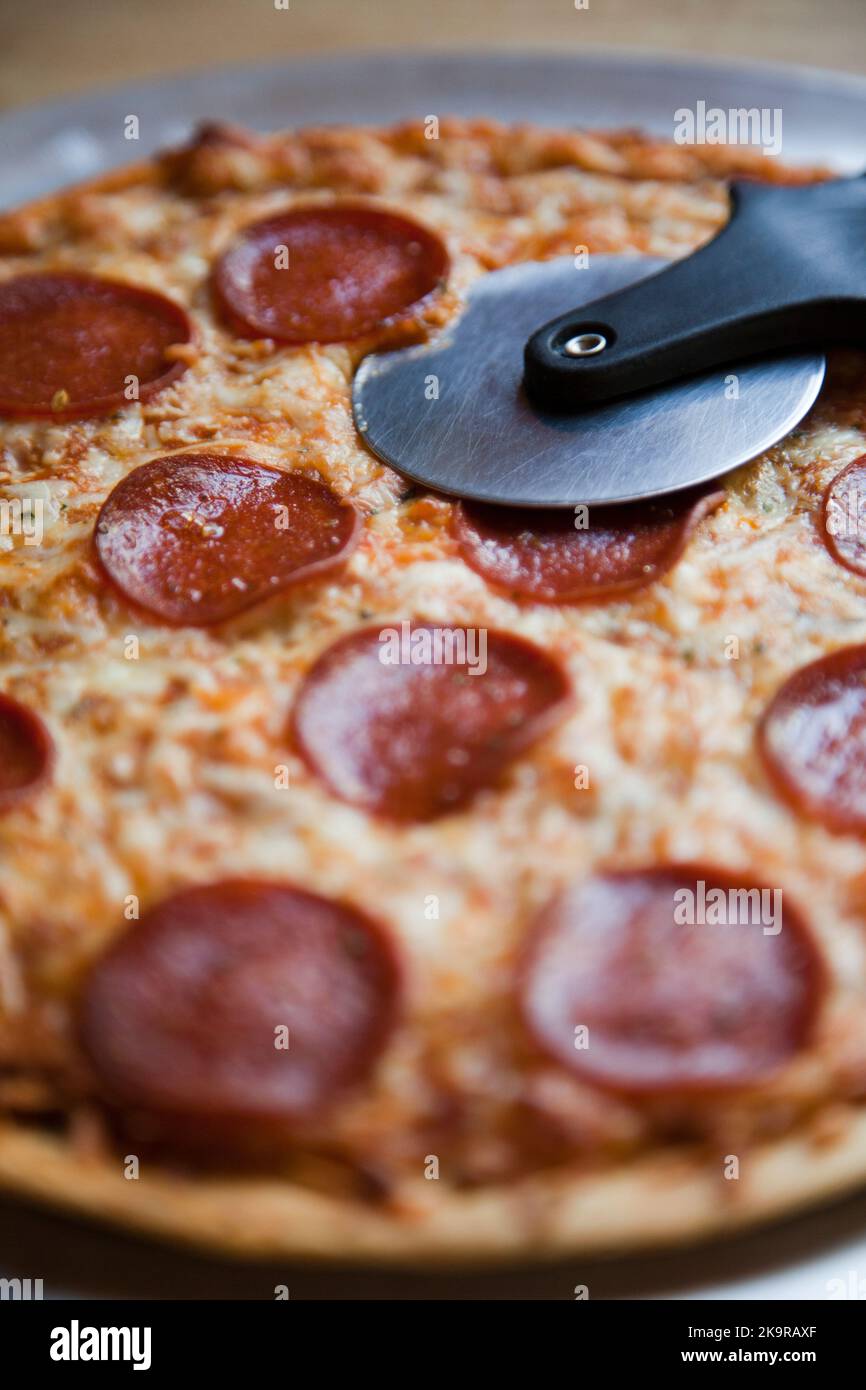 Baked pepperoni and cheese thin crust pizza with a pizza cutter Stock ...