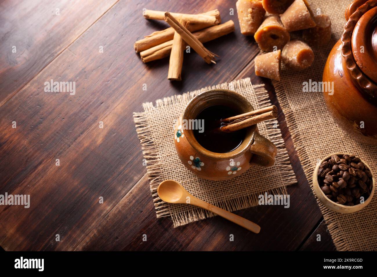 Authentic homemade mexican coffee (cafe de olla) served in traditional handmade clay mug (Jarrito de barro) on rustic wooden table. Stock Photo