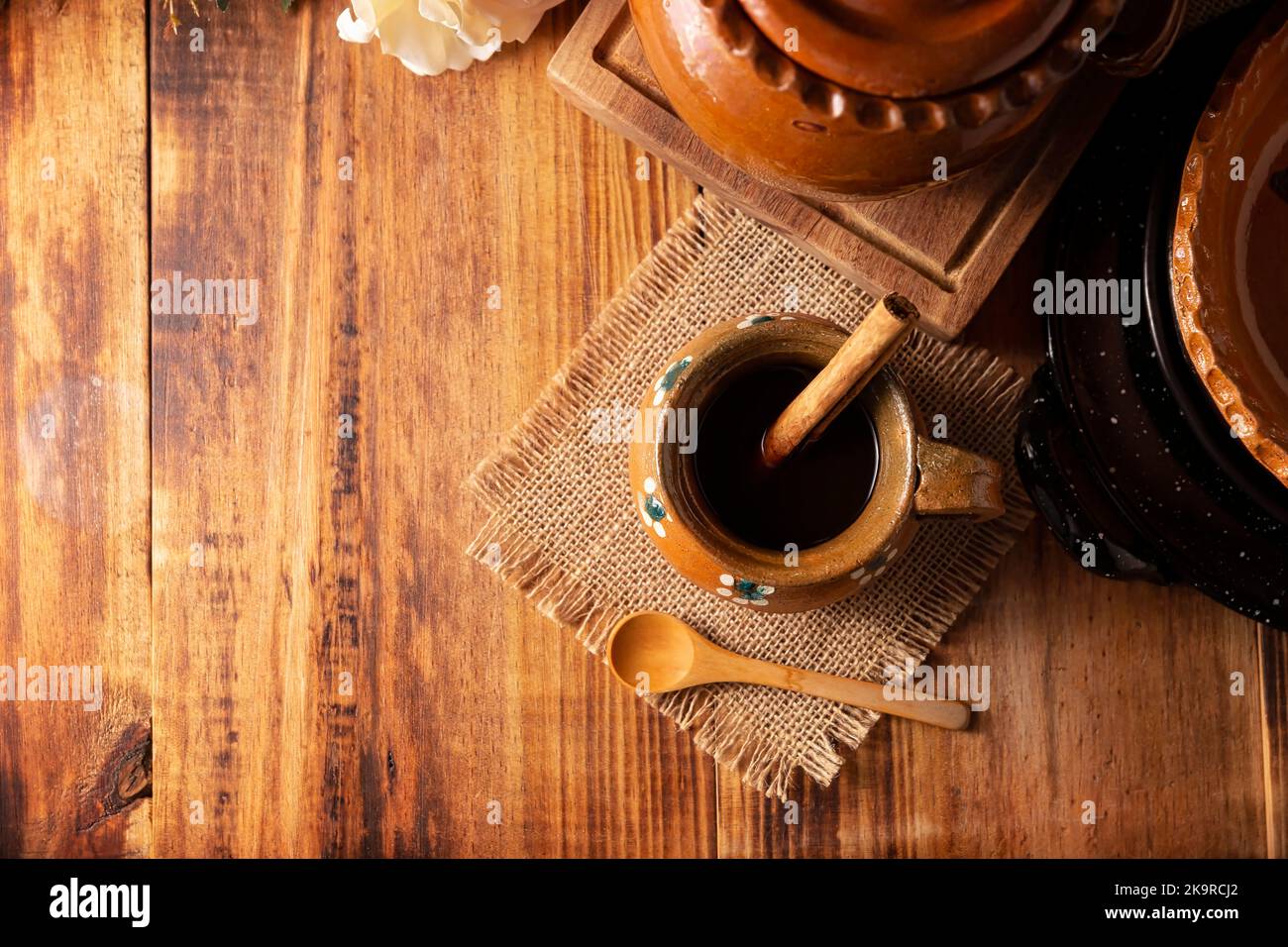 Authentic homemade mexican coffee (cafe de olla) served in traditional handmade clay mug (Jarrito de barro) on rustic wooden table. Stock Photo