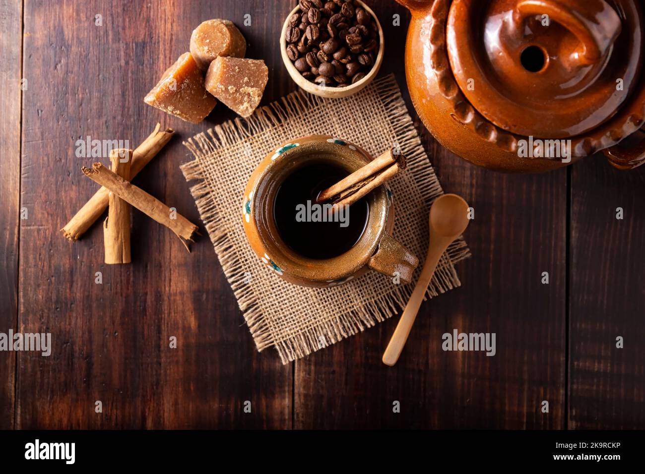 Authentic homemade mexican coffee (cafe de olla) served in traditional handmade clay mug (Jarrito de barro) on rustic wooden table. Stock Photo