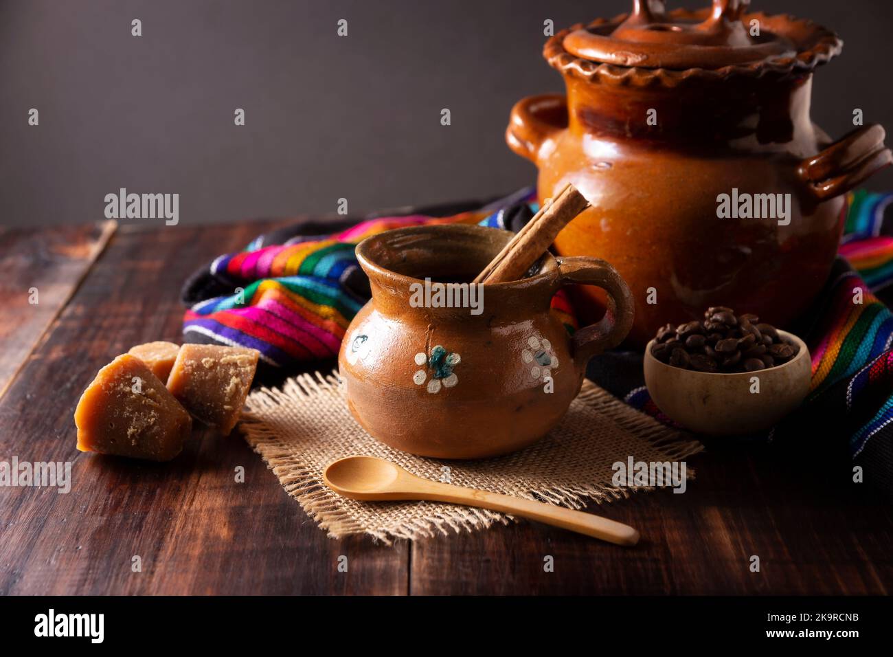 Authentic homemade mexican coffee (cafe de olla) served in traditional handmade clay mug (Jarrito de barro) on rustic wooden table. Stock Photo