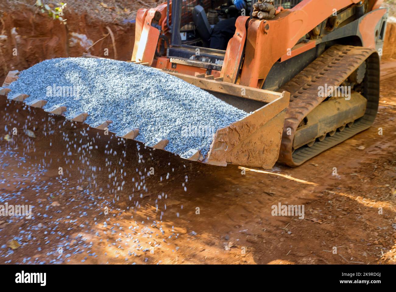 An excavator bucket rakes in crushed stone the excavator is picking up