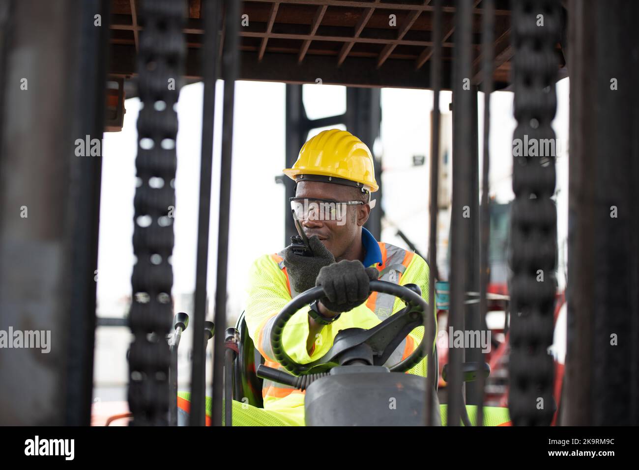 Worker man driving forklift in industrial container warehouse. Stock Photo