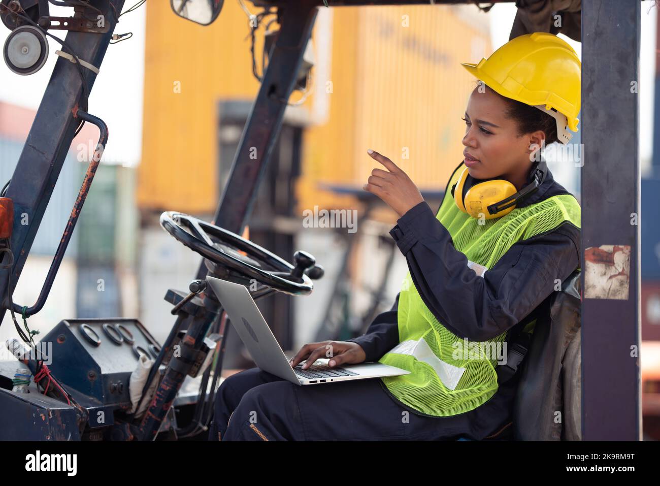 Female worker driving forklift in industrial container warehouse Stock