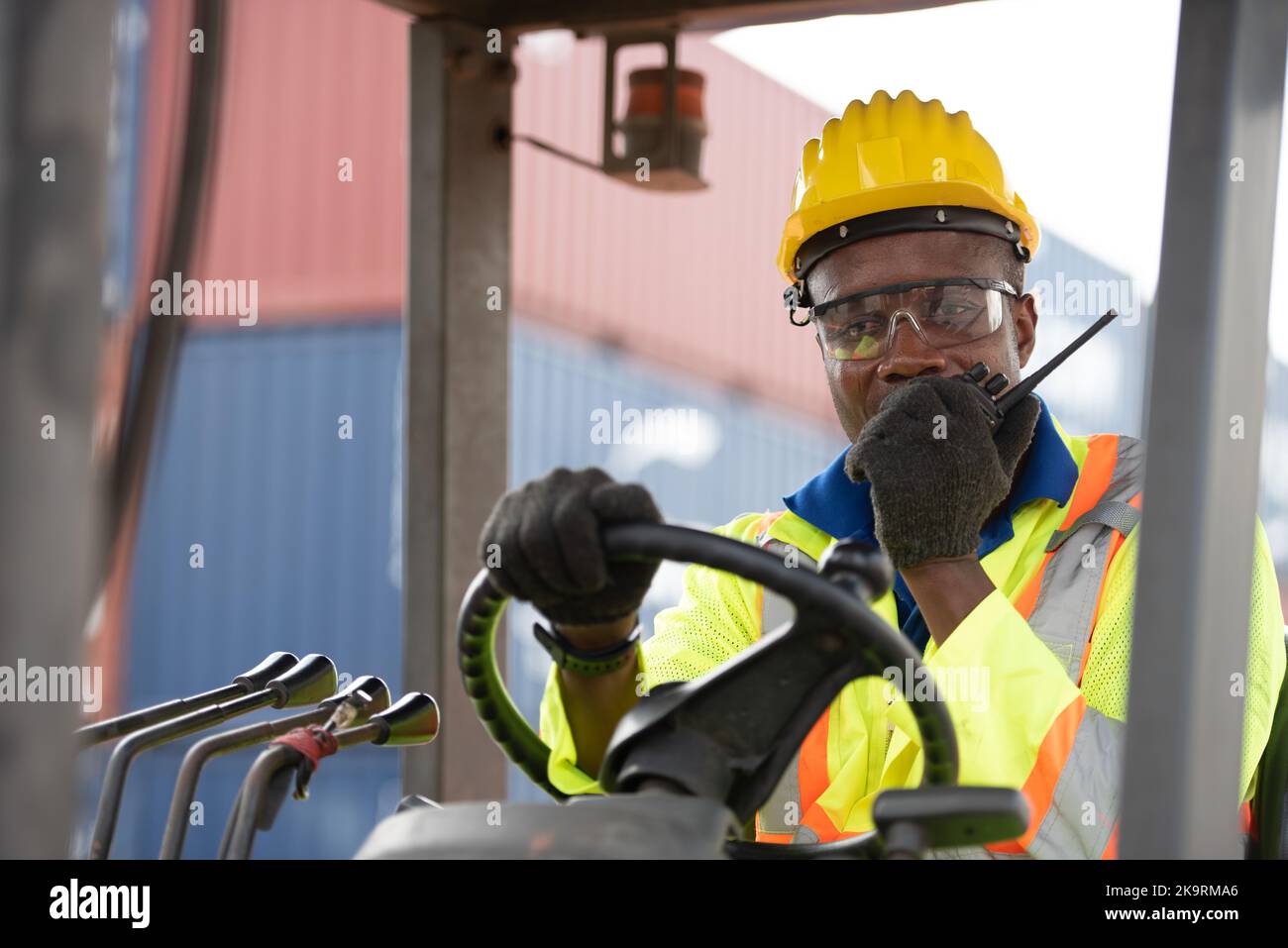 Worker man driving forklift in industrial container warehouse. Stock Photo