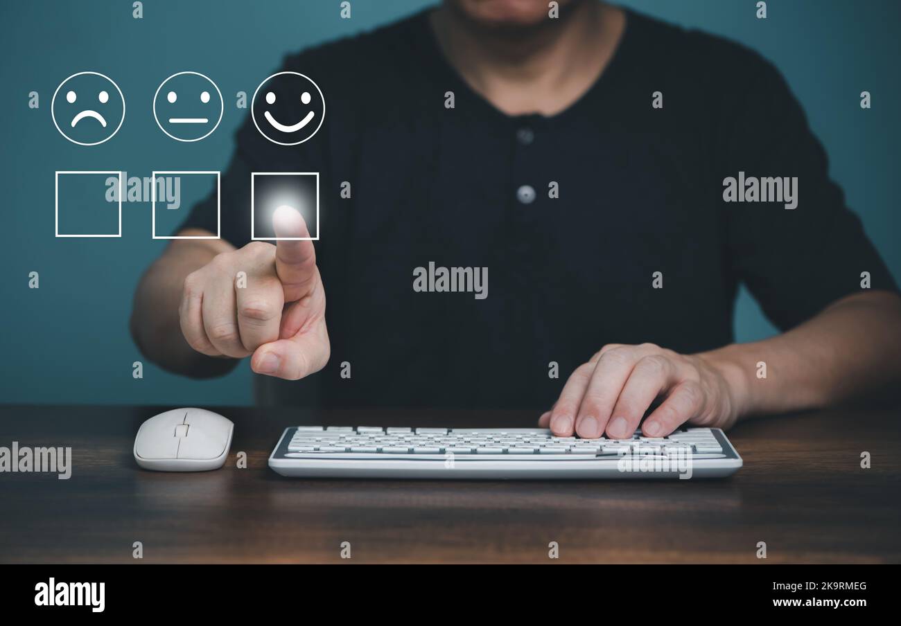 Customer service and satisfaction concept ,Business people using computer and touching the virtual screen on the happy Smiley face icon to give satisf Stock Photo