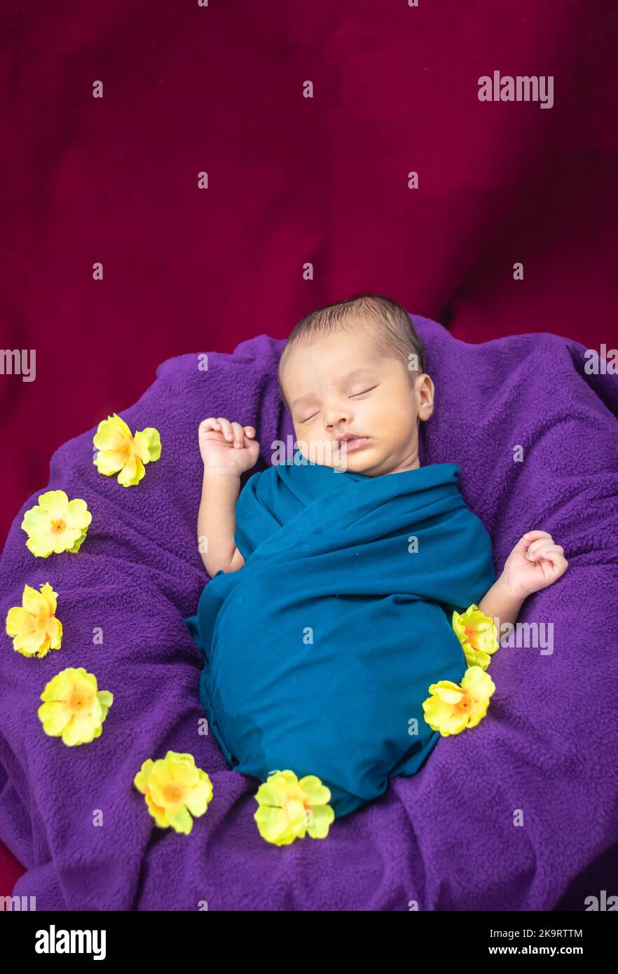 cute newborn baby sleeping in baby wrap with flowers in unique style