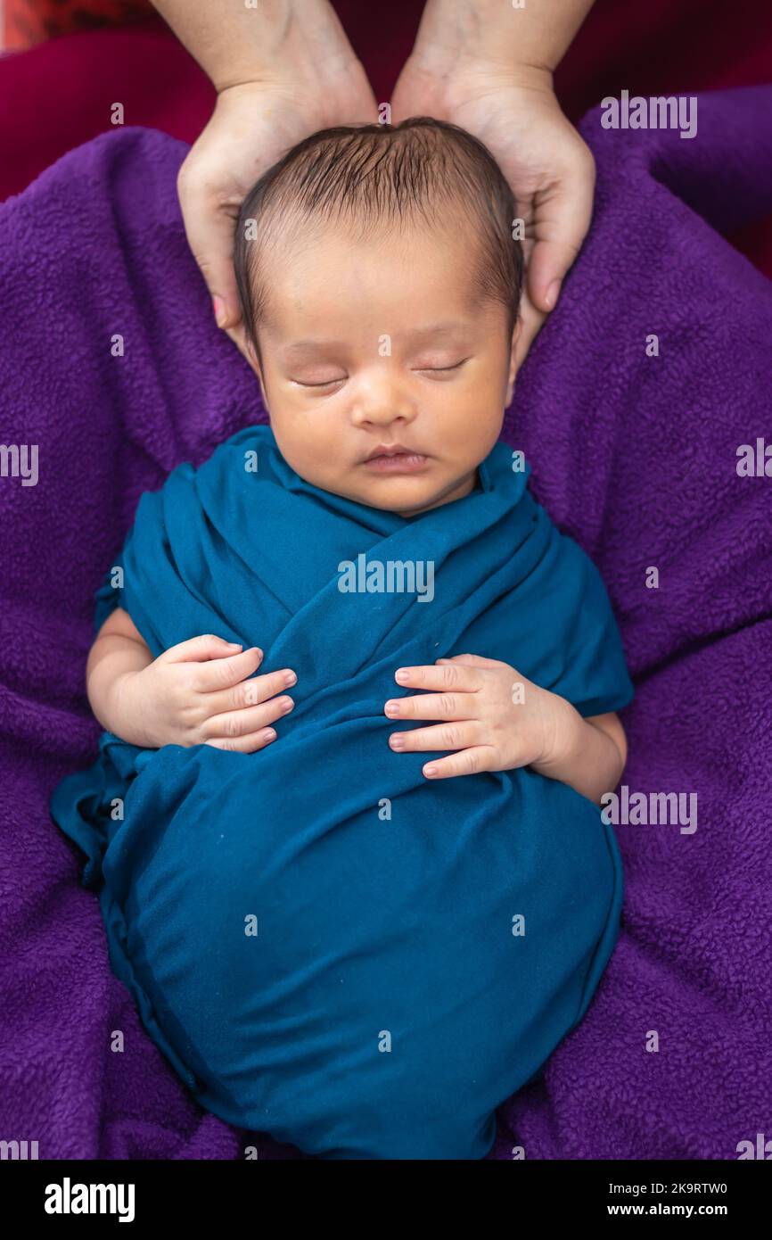 mom holding cute newborn baby sleeping in baby wrap top angle shot