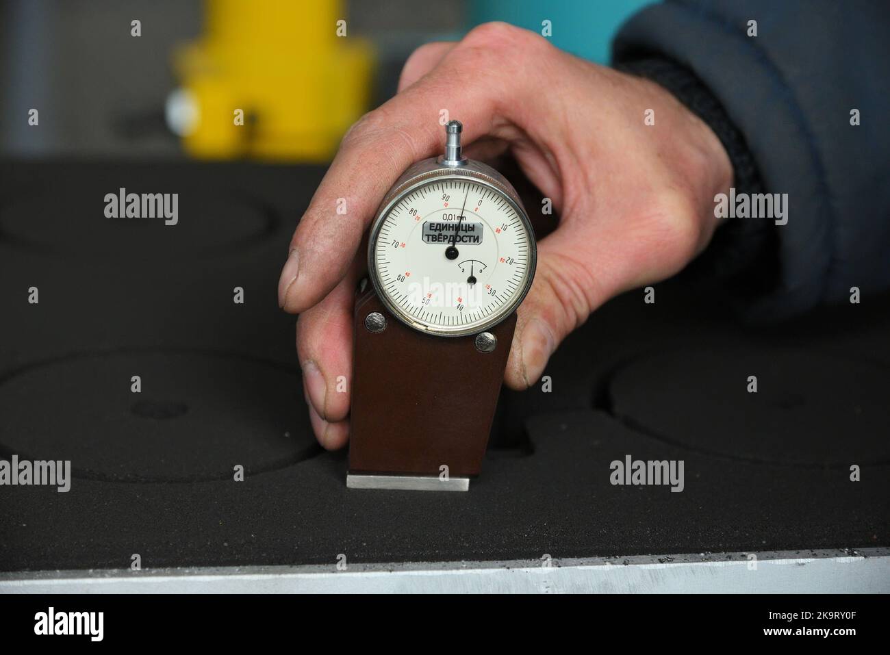 worker's hand holds a dial gauge for measuring the hardness  Stock Photo