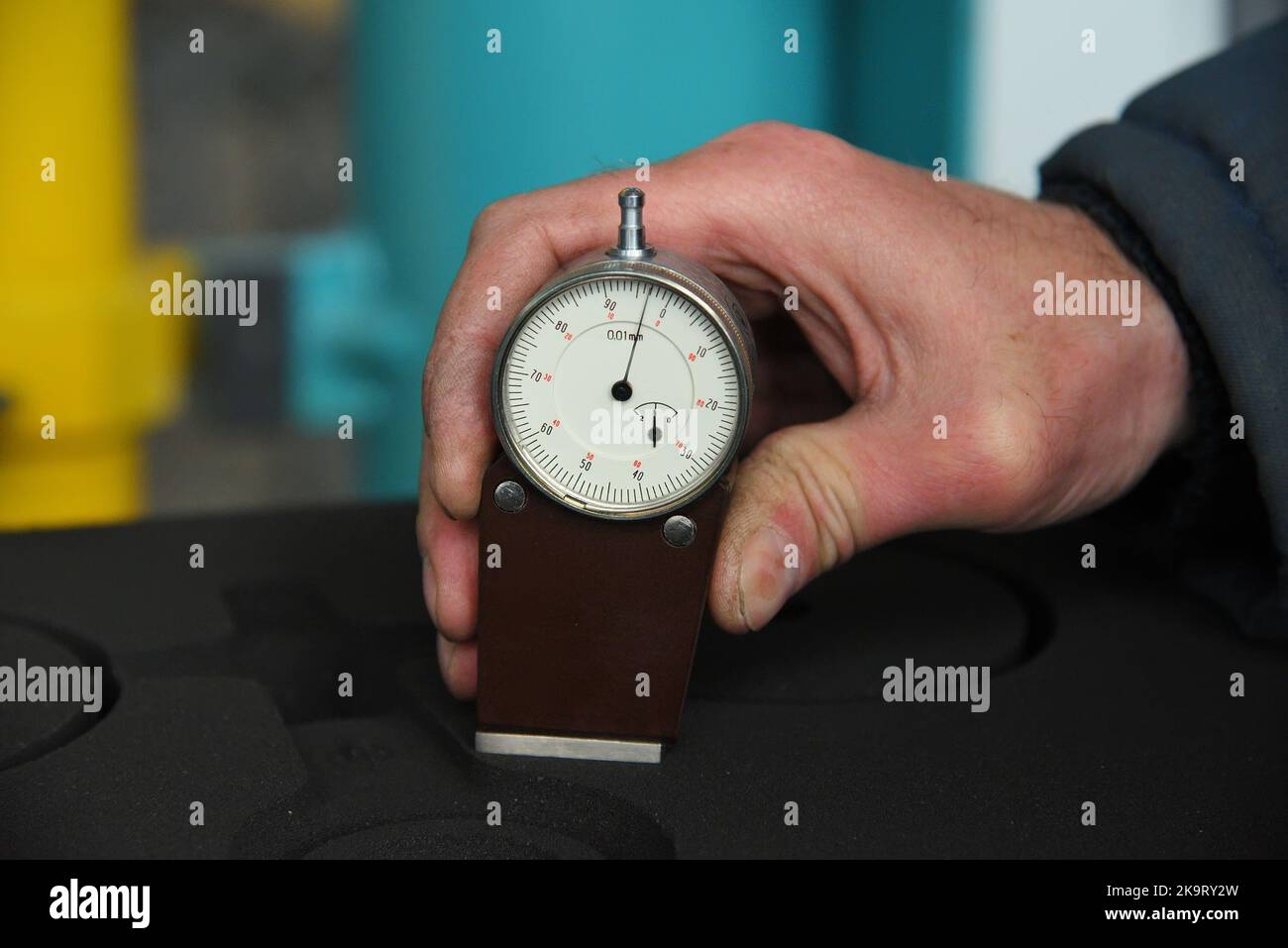 worker's hand holds a dial gauge for measuring the hardness  Stock Photo