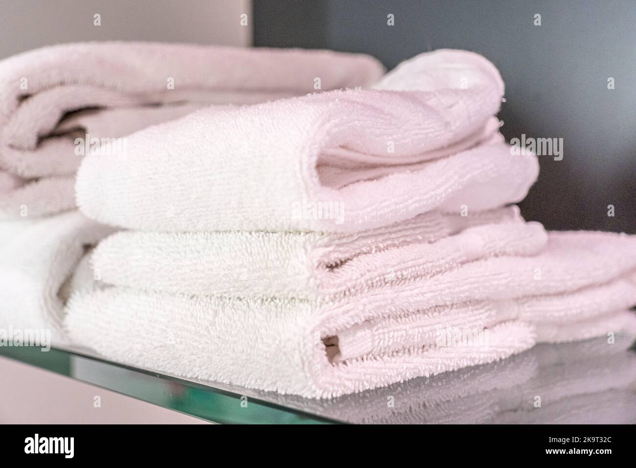 Stacked clean fluffy towels in a bathroom Stock Photo by FabrikaPhoto