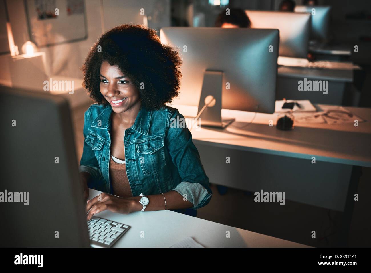 She has no problem working late. High angle shot of an attractive young female designer working on her computer in the office. Stock Photo