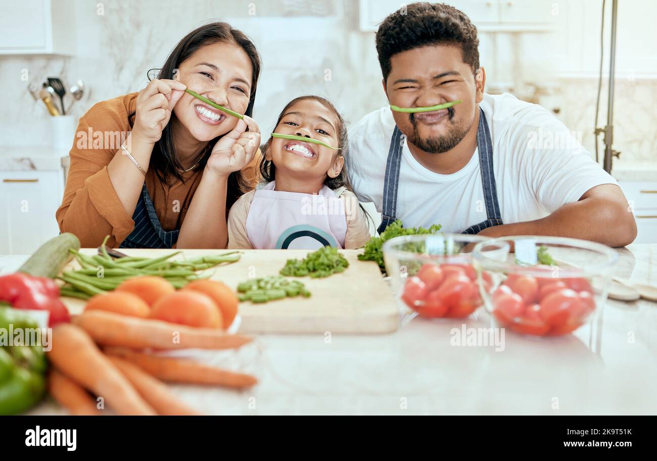 Cooking, family and comic portrait in kitchen for crazy, goofy and silly fun together with smile. Food, asian and bonding with funny vegetable face of Stock Photo