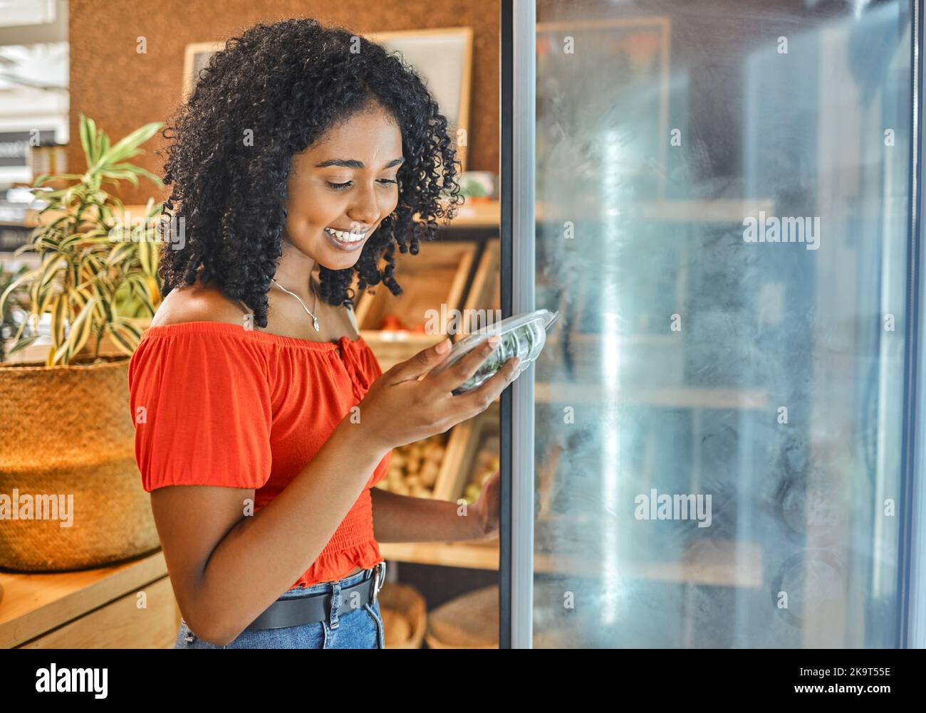 Supermarket, grocery store and customer black woman shopping for healthy food in fridge happy with price discount, sale or promotion. Groceries, small Stock Photo