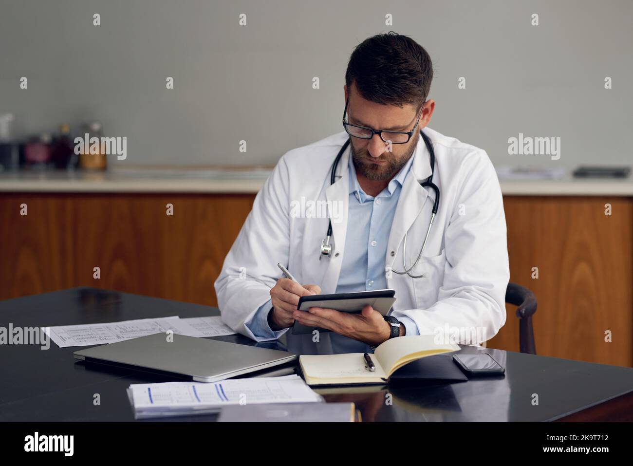 Wireless technology makes record-keeping a breeze. a handsome male doctor working on his tablet while sitting in his office. Stock Photo