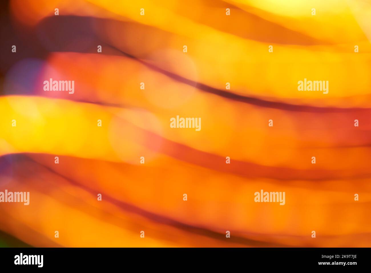 Abstract blurred colorful lights background, dynamic flowing design in warm orange vivid colors. Stock Photo