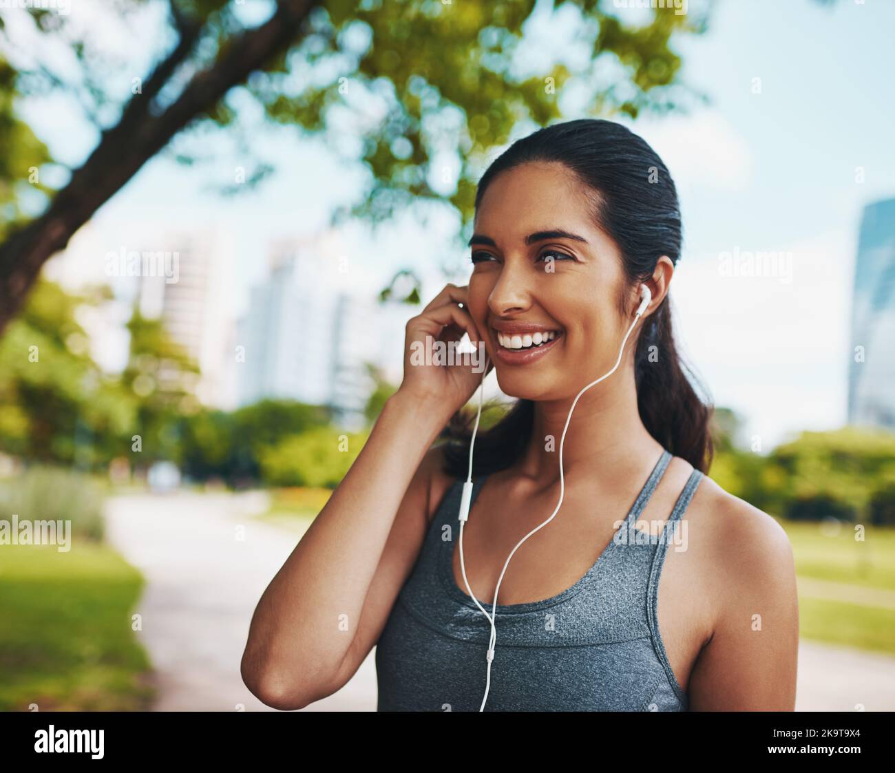 If music be the food of fitness...an attractive young sportswoman listening to music while working out outdoors in the city. Stock Photo