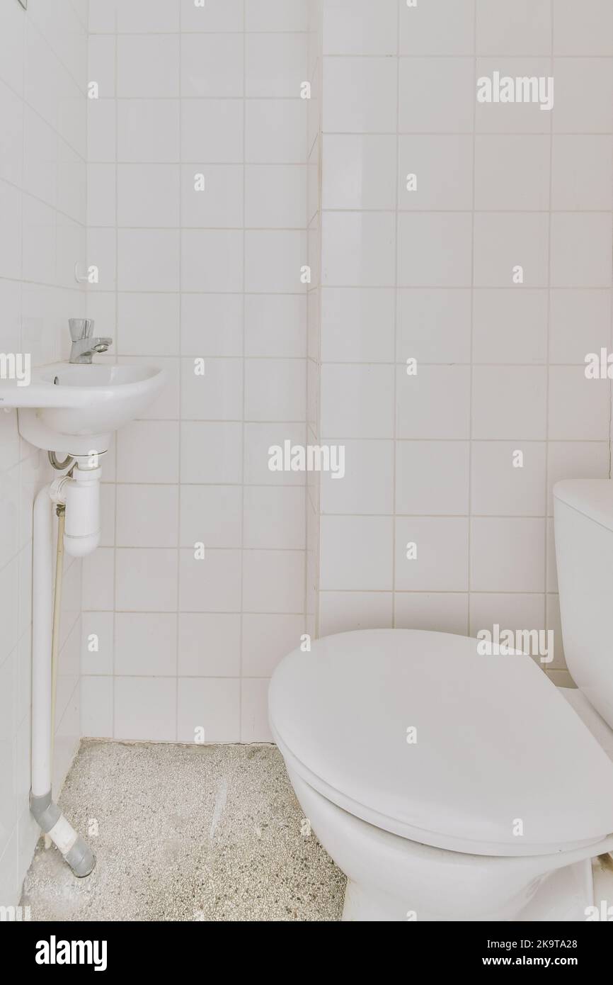 Interior of narrow bathroom and toilet with showroom, sink and wall hung toilet with white walls and checkered floor Stock Photo