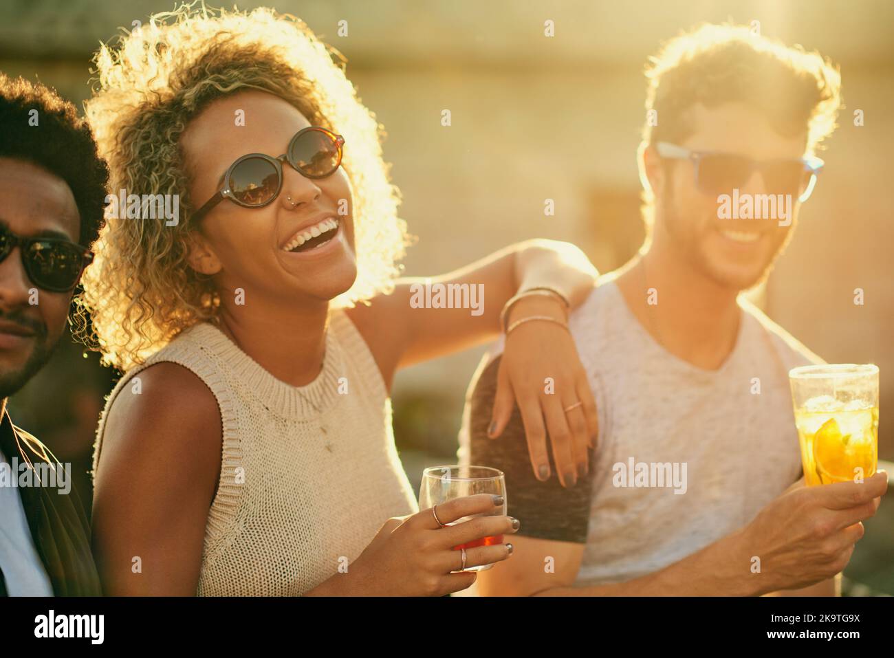 This was a great idea, lets do it again sometime. a group of young diverse friends having a drink and spending the day outside on a rooftop. Stock Photo