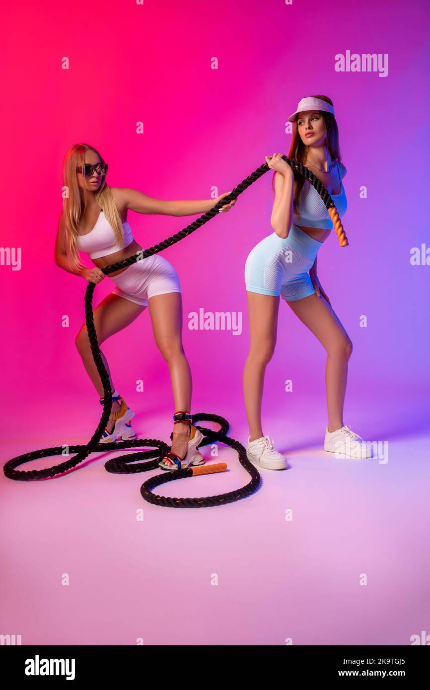 Slim female athlete exercising with ropes Stock Photo
