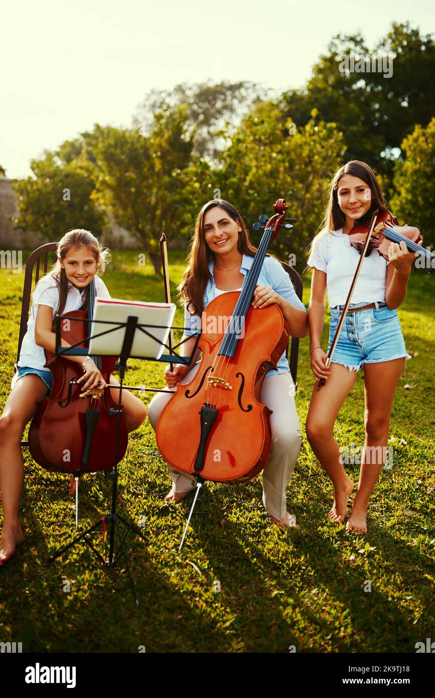 Music lifts the spirit and enlightens the soul. a beautiful mother playing instruments with her adorable daughters outdoors. Stock Photo