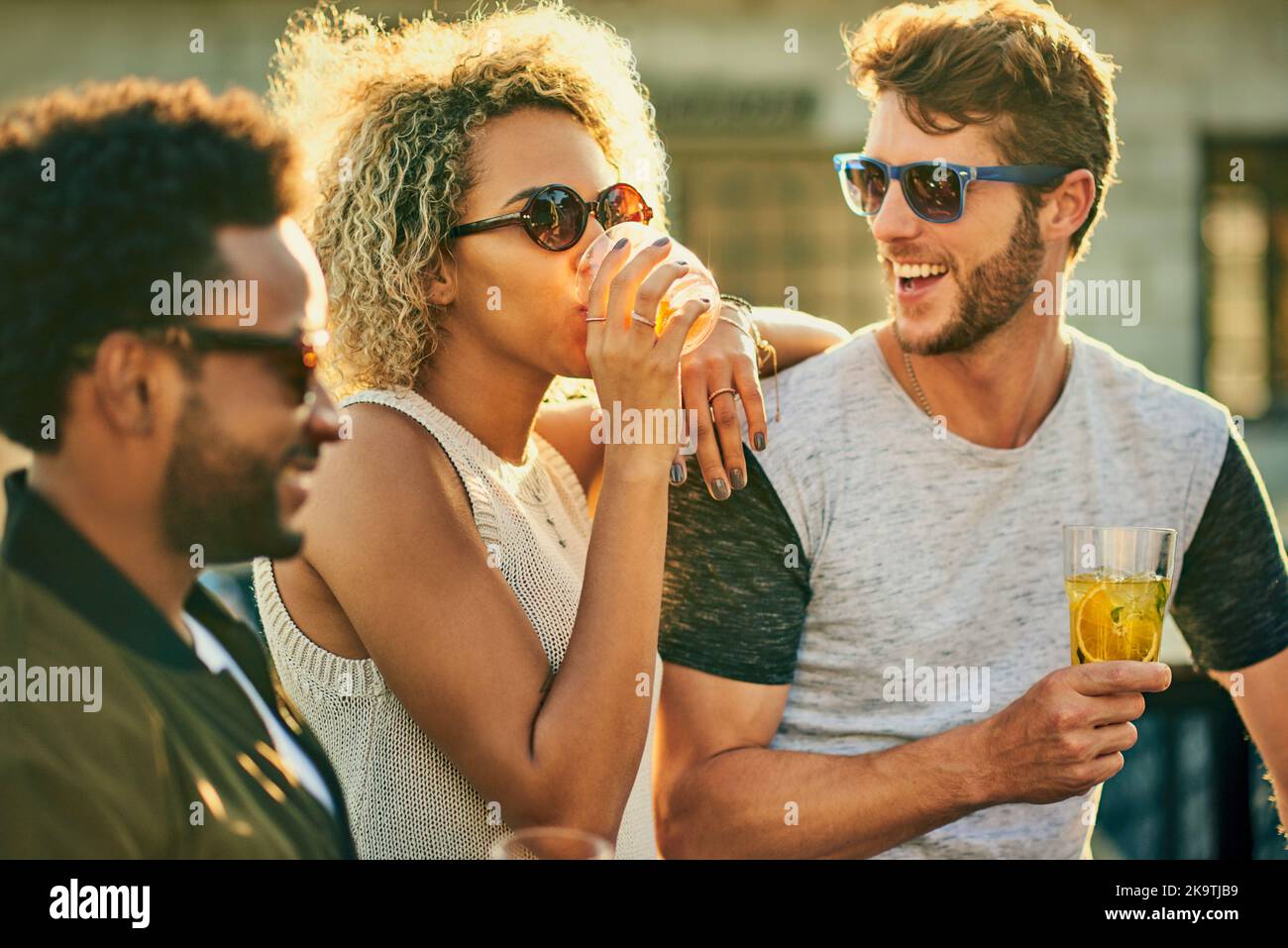 Having the times of their life. a group of young friends having a drink and spending the day outside on a rooftop. Stock Photo
