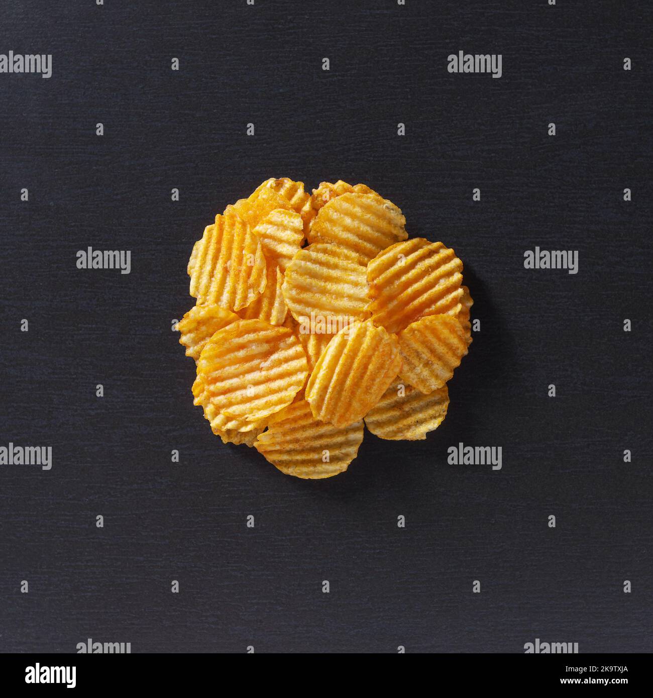 Potato chips on a black stone background, top view Stock Photo
