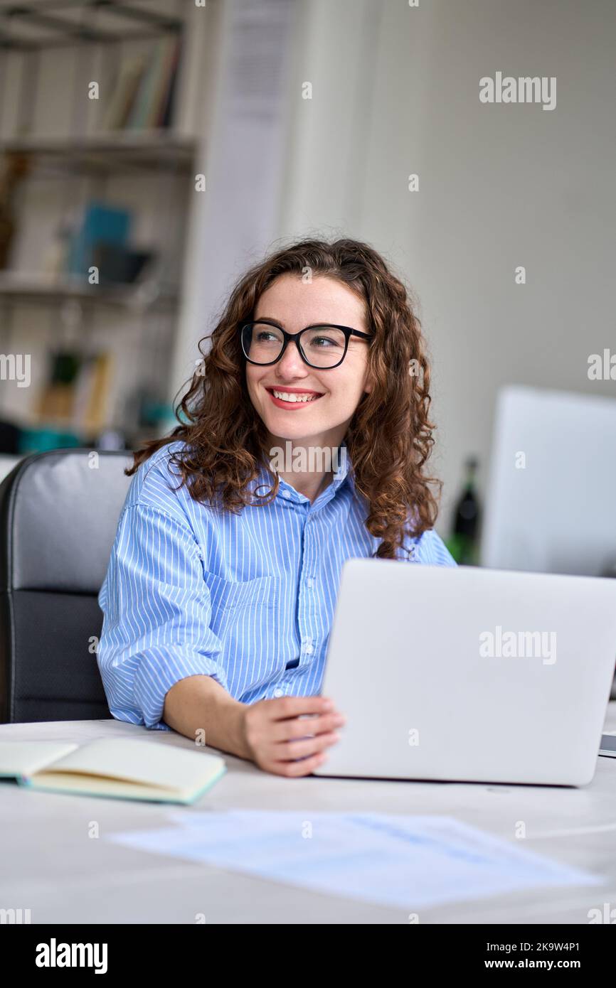 Young happy business woman sitting at office desk working on laptop ...