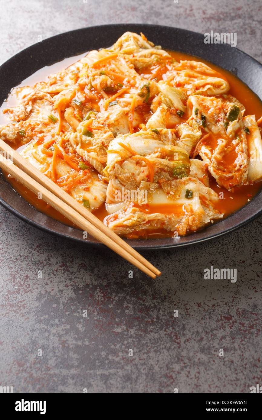 Chinese cabbage kimchi close-up in a black dish on a dark background. Vertical Stock Photo