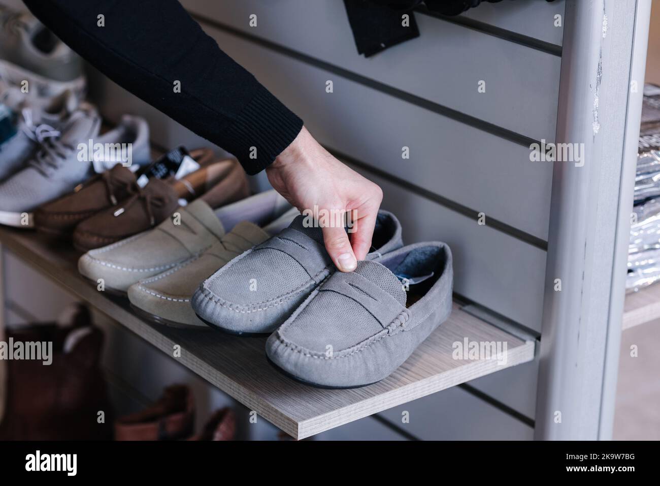 Hand of human taking gray moccasins from the shelf in clothes store Stock Photo