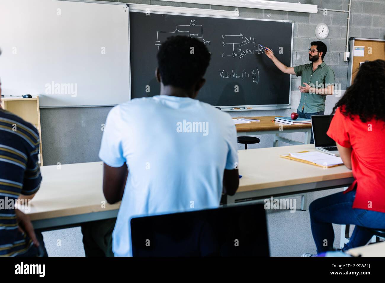 Young male high school tutor teaching electronic lesson to students Stock Photo