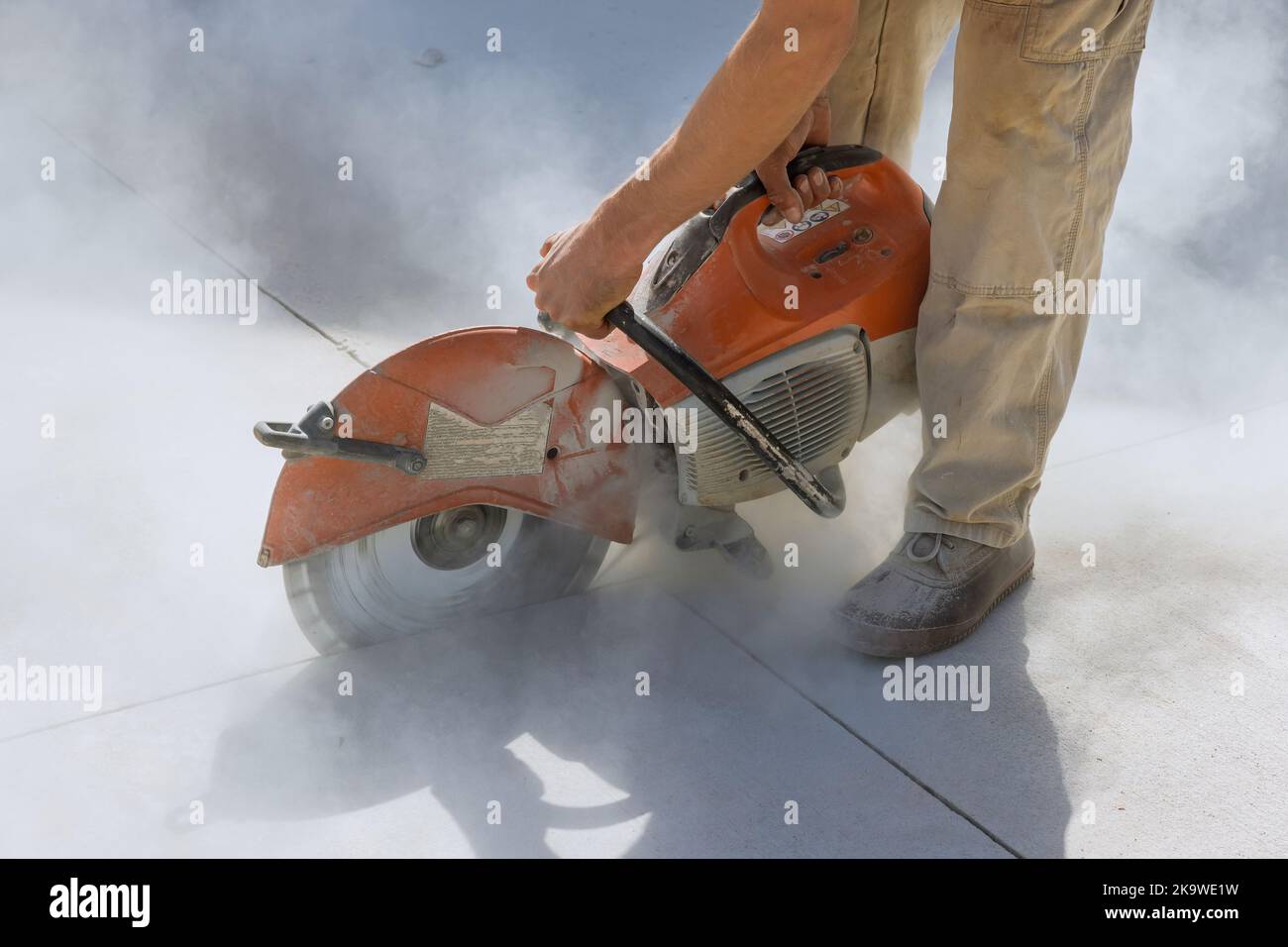 Diamond blade saws are used by construction workers to cut concrete sidewalk Stock Photo