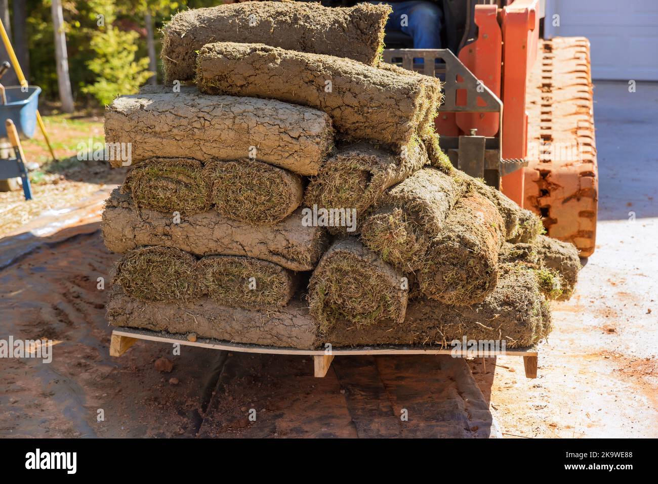 On construction site boom forklift truck is being used to unload green grass turf rolls in