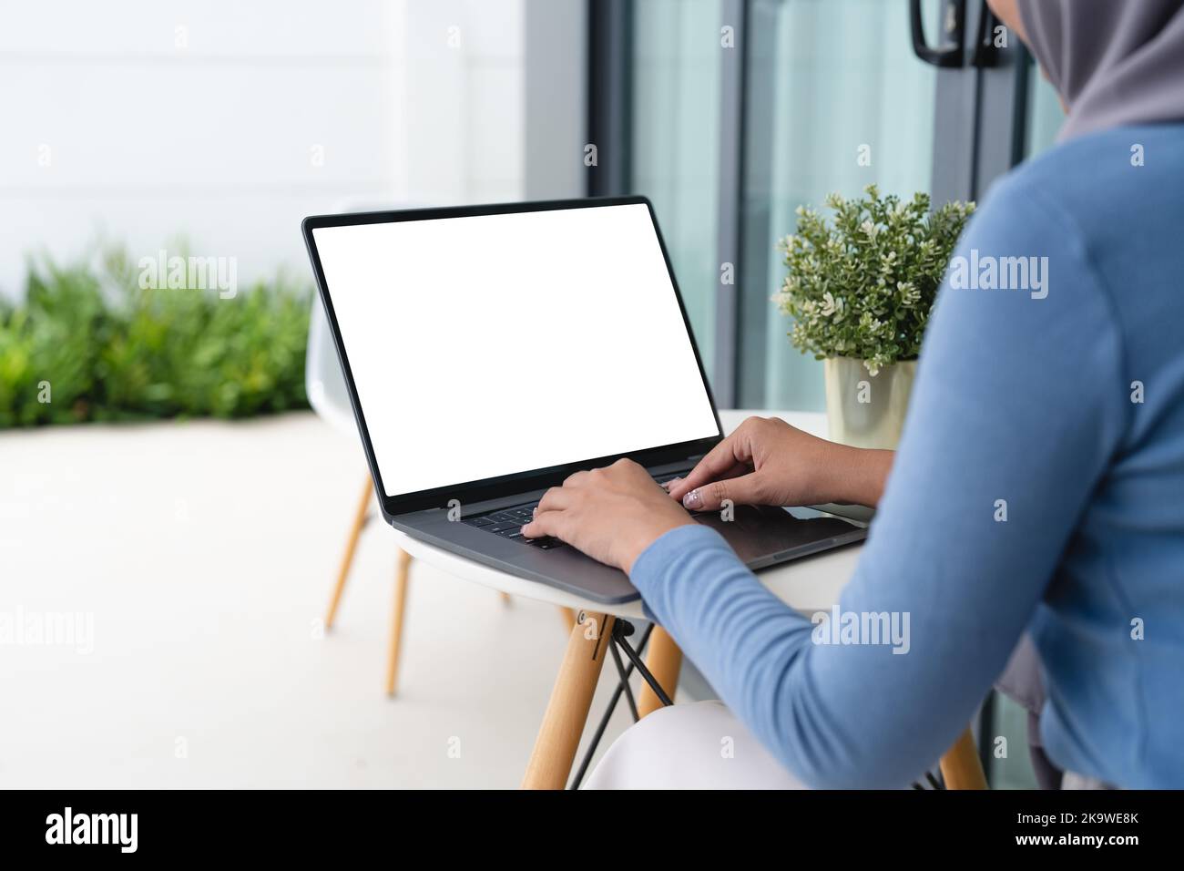 Mockup image of hand using laptop with blank white screen on table ...