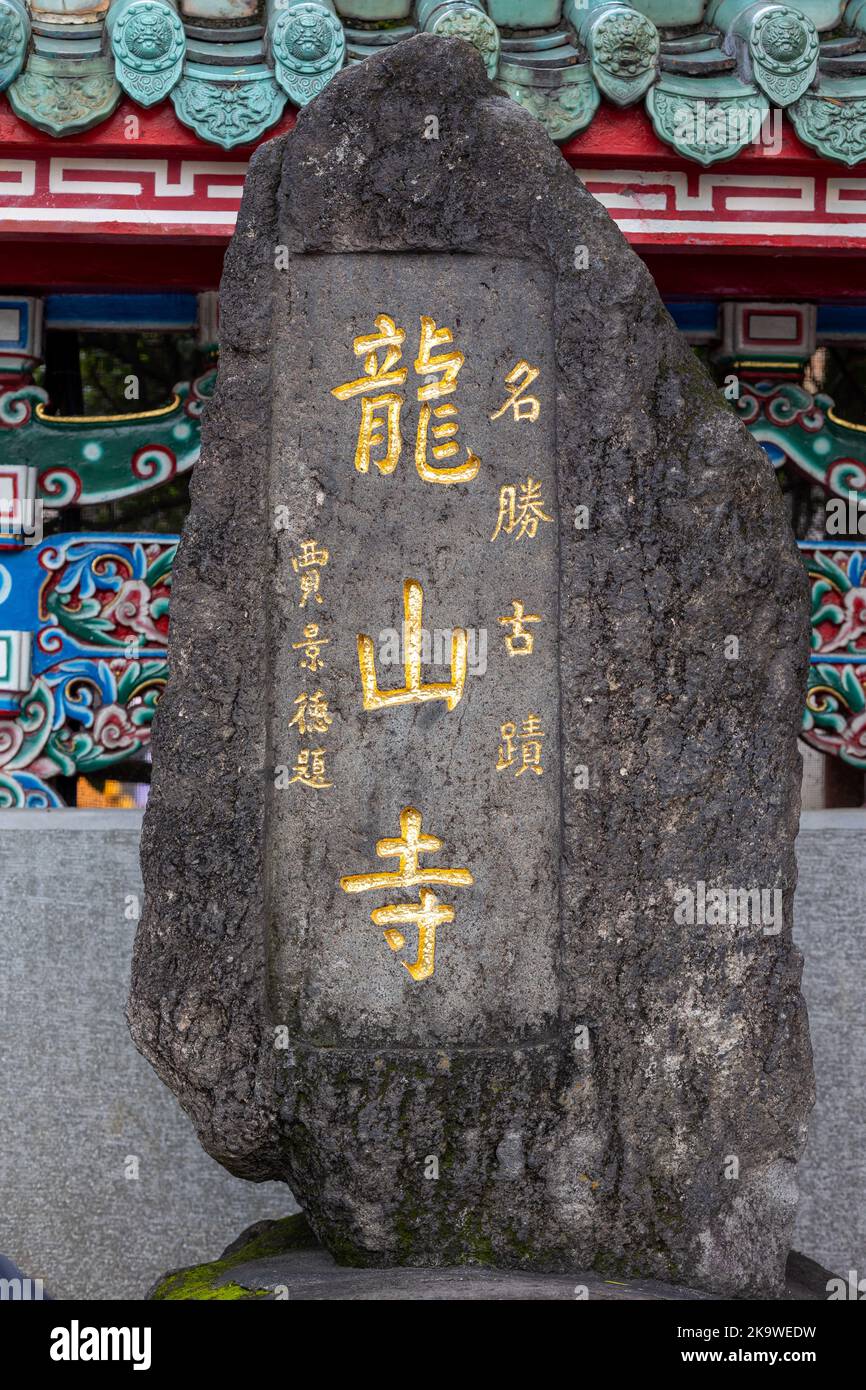 A rock stele at the entrance to Longshan Temple in Taipei with the temple's name in Chinese carved on it. Stock Photo