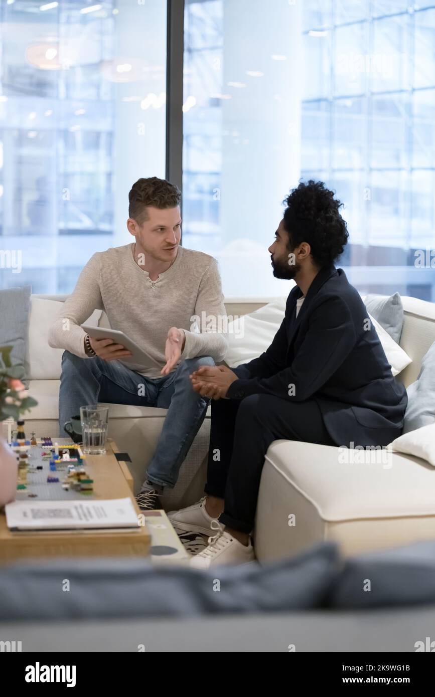 Two multiracial businessmen discuss on-line presentation on tablet Stock Photo