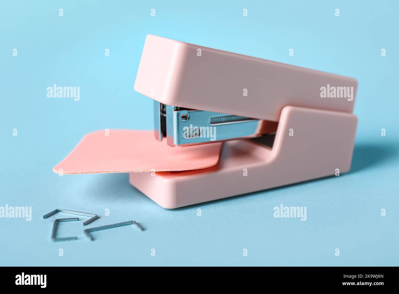 Pink office stapler with sticky notes on color background Stock Photo ...