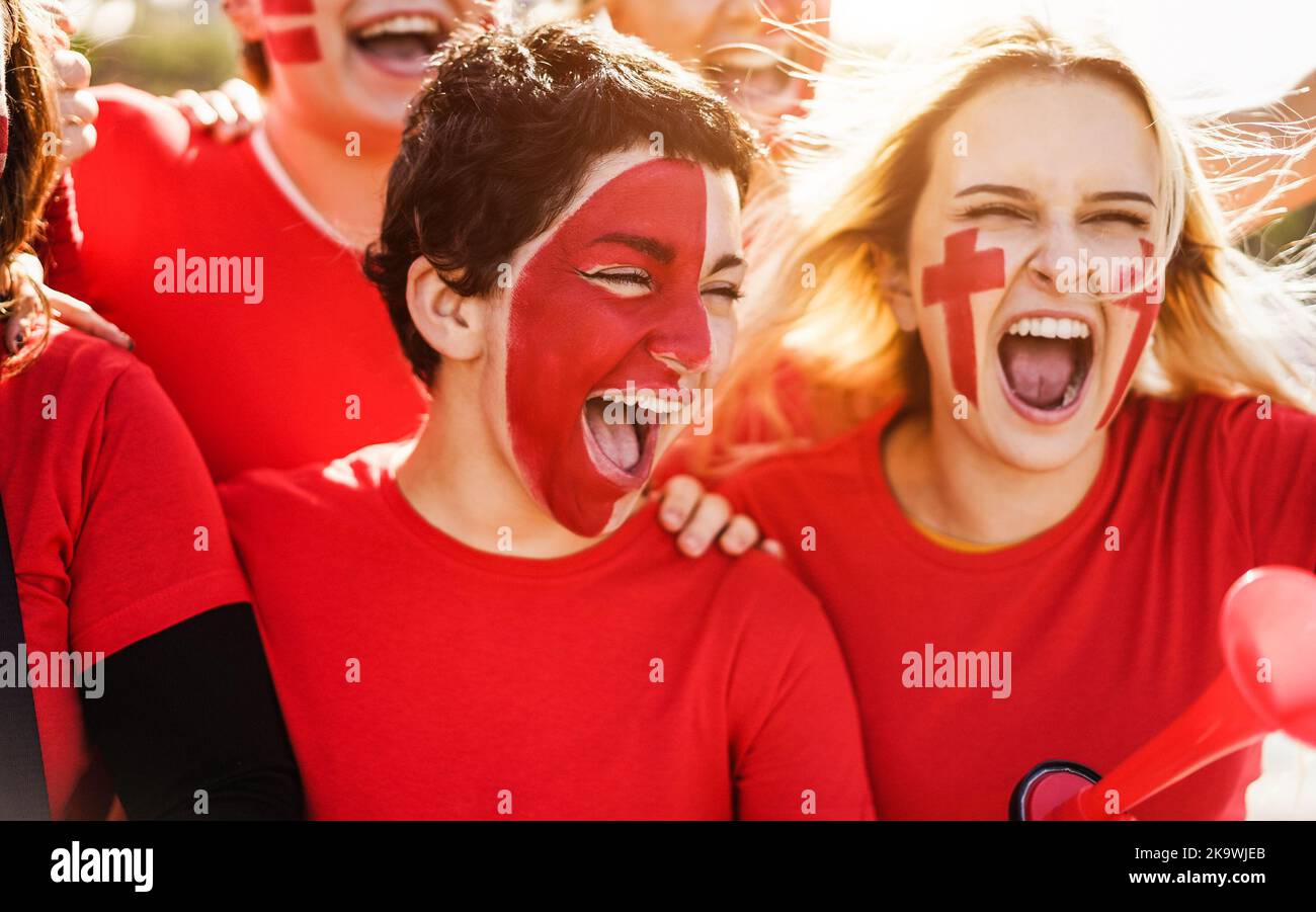 Red sport football fans screaming while supporting their team out of the stadium - Focus on center girl face Stock Photo