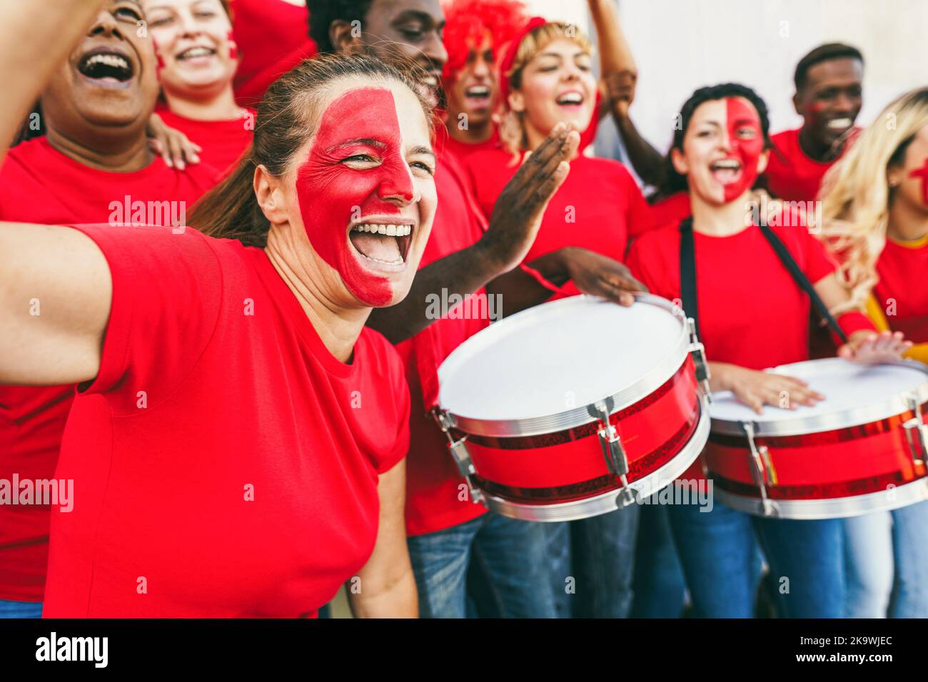 Multiracial red sport fans screaming while supporting their team - Football supporters having fun at competition event - Soft focus on senior woman fa Stock Photo