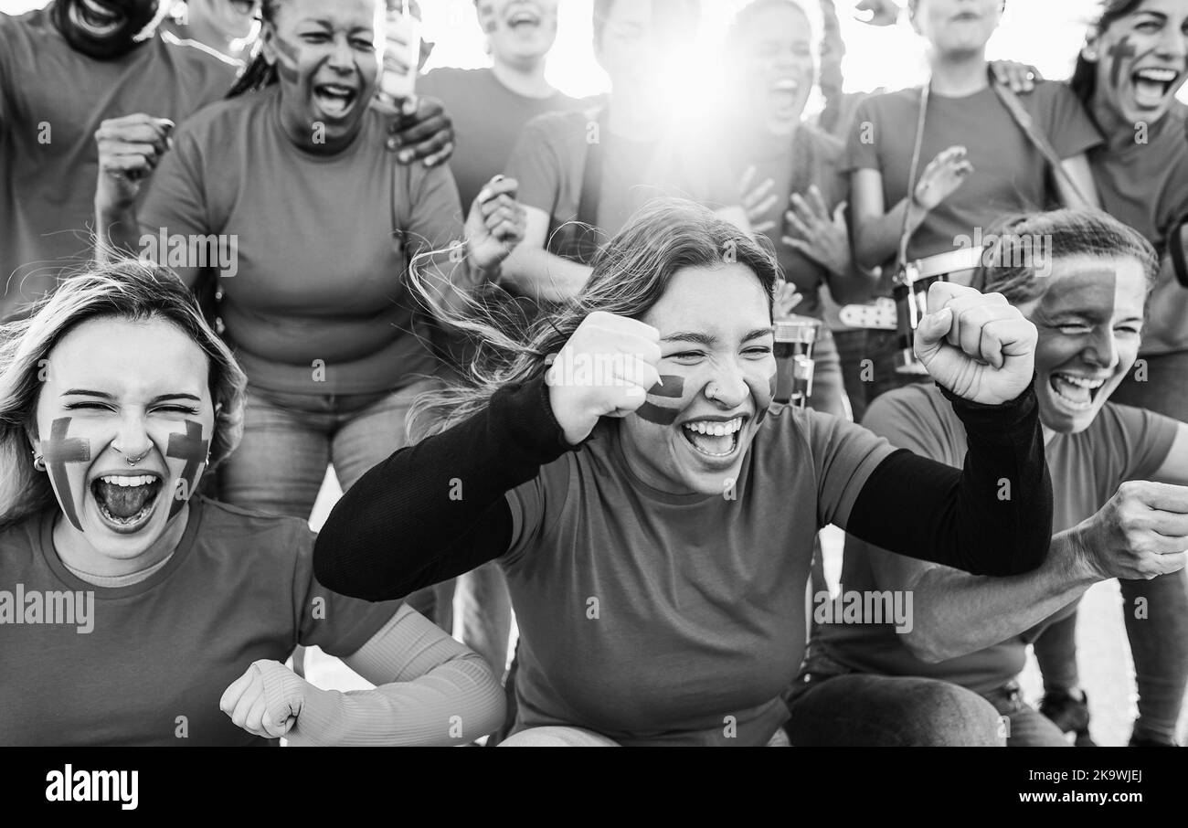Multiracial sport fans screaming while supporting their team - Football supporters having fun at competition event - Focus on left girl face - Black a Stock Photo