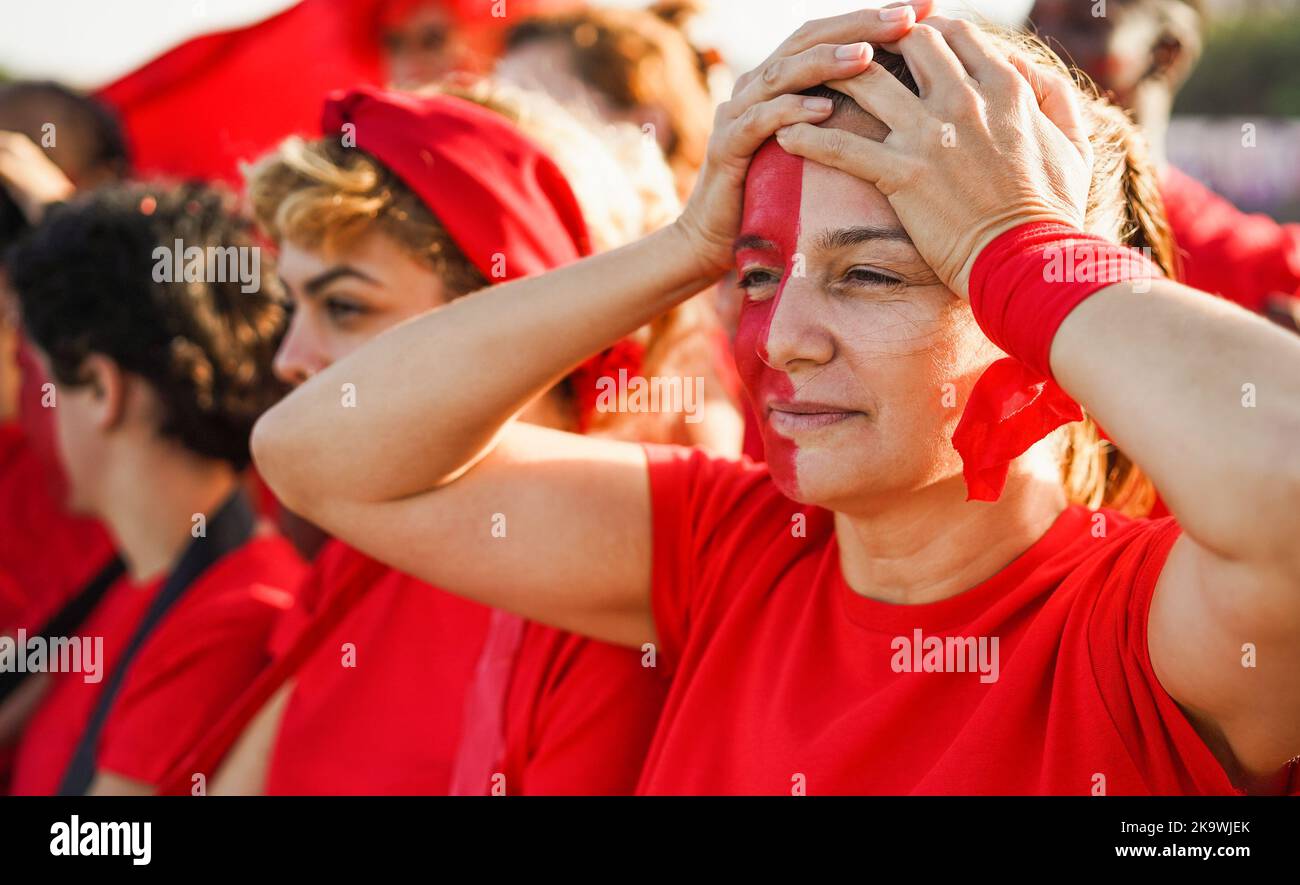 Red sport football fans disappointed while watching their team losing match game at stadium - Focus on senior woman eye Stock Photo