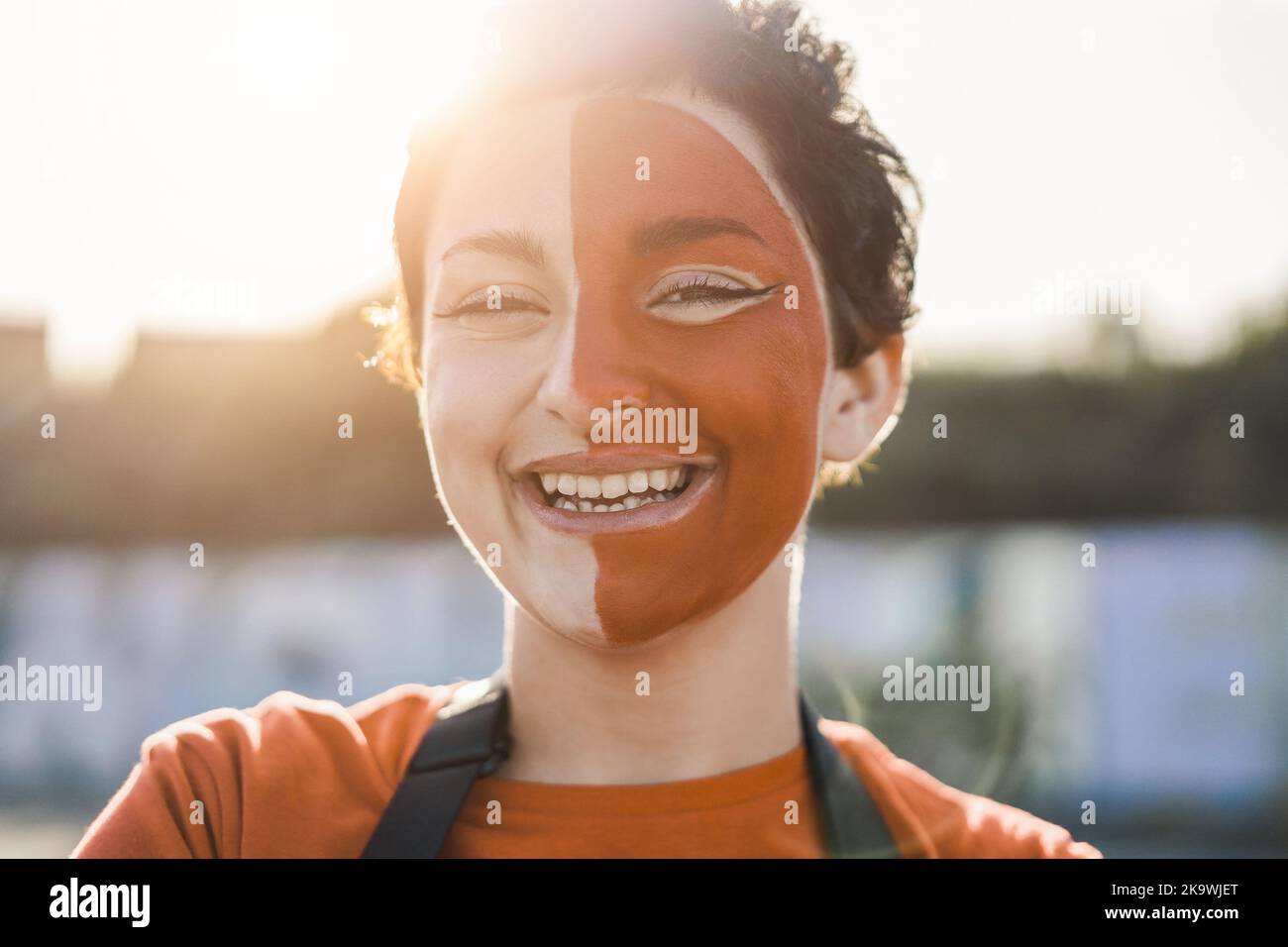 Orange sport fan smiling at camera out of the stadium before football match - Main focus on right eye Stock Photo