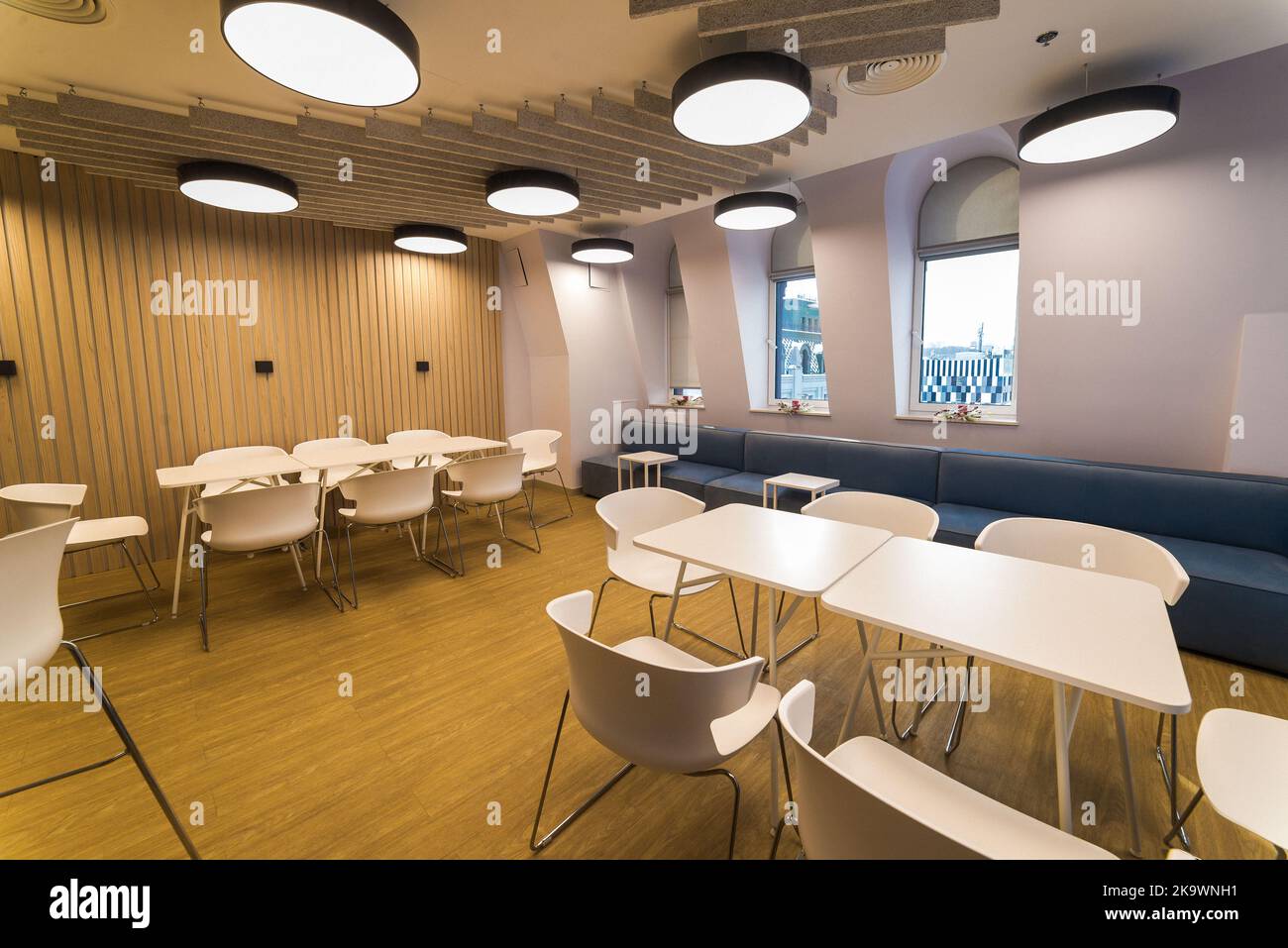 Meeting zone in the office in a loft style with white brick walls and concrete columns. Zone has a large wooden table with gray chairs and glass parti Stock Photo