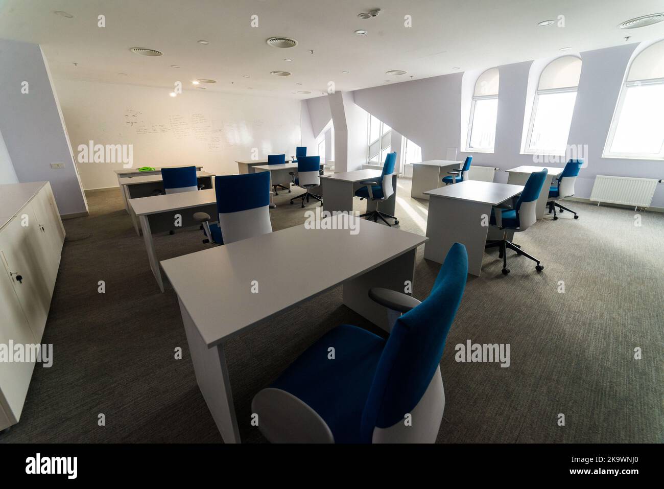 Meeting zone in the office in a loft style with white brick walls and concrete columns. Zone has a large wooden table with gray chairs and glass parti Stock Photo