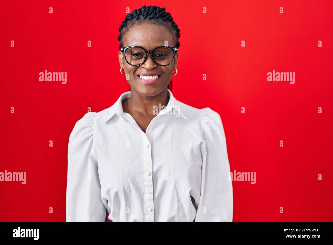African woman with braids standing over red background with a happy and ...