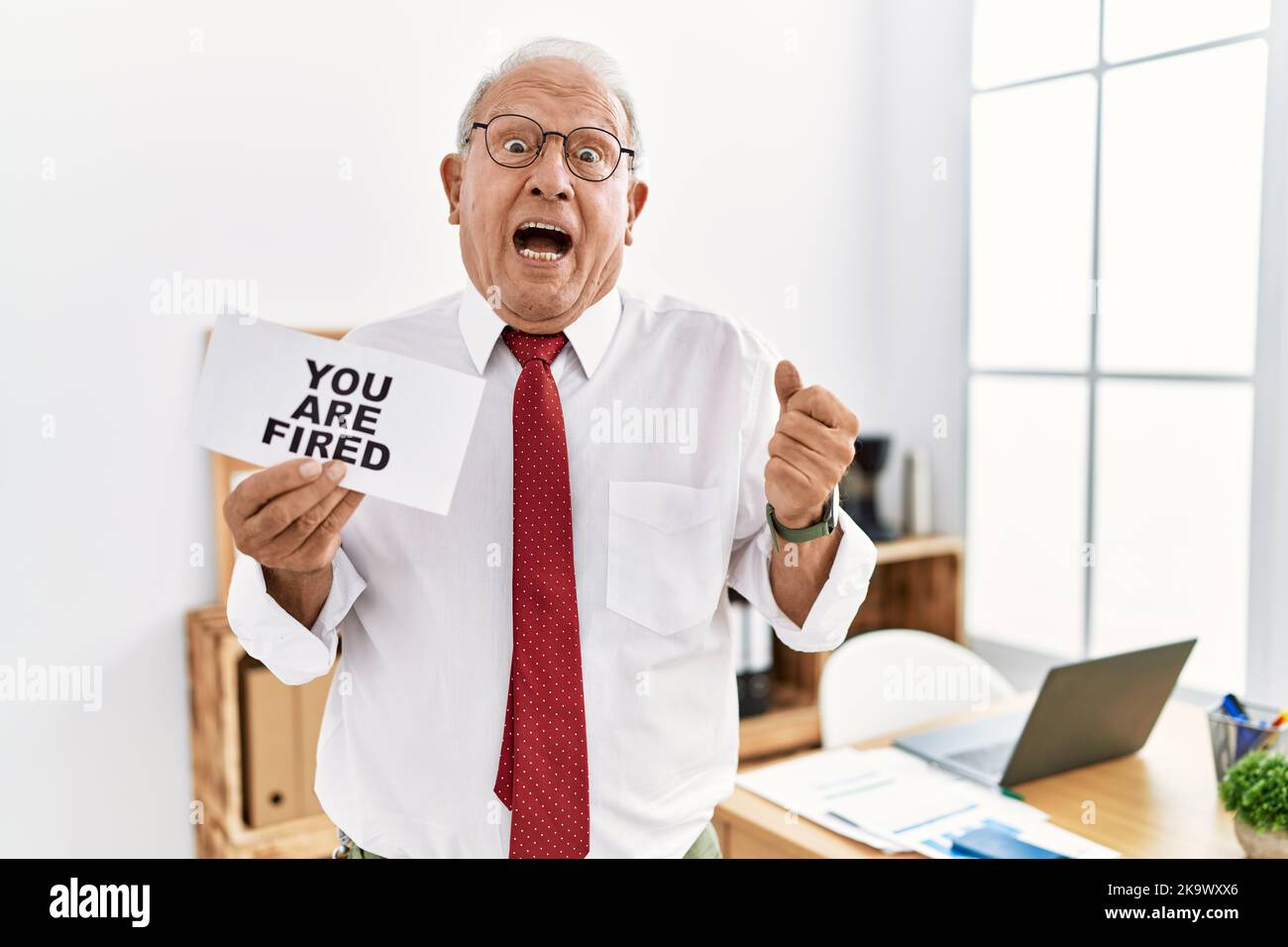 Senior business man holding you are fired banner at the office ...
