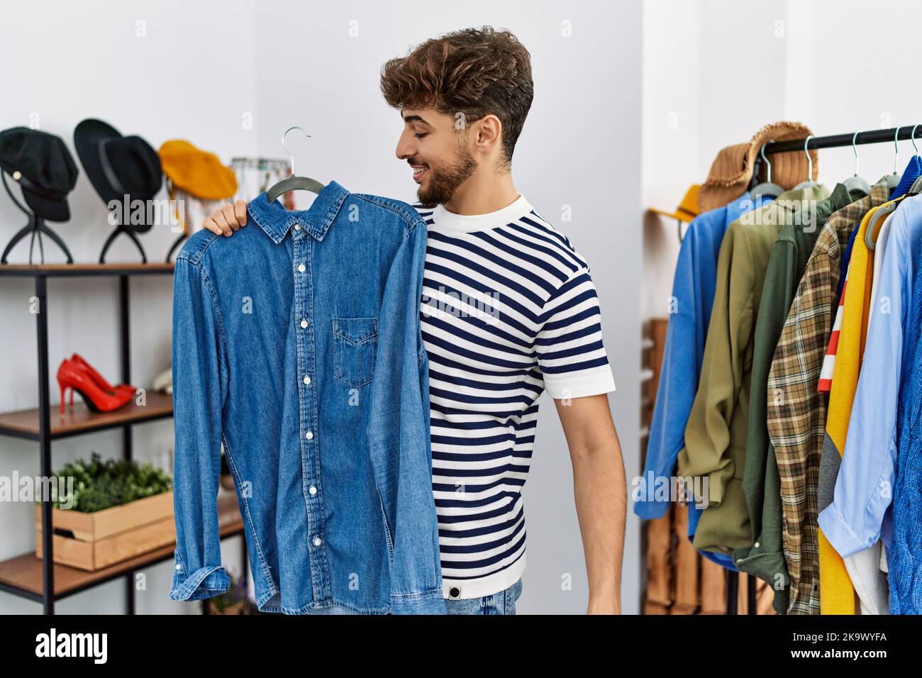 Young arab man customer holding shirt shopping at clothing store Stock ...