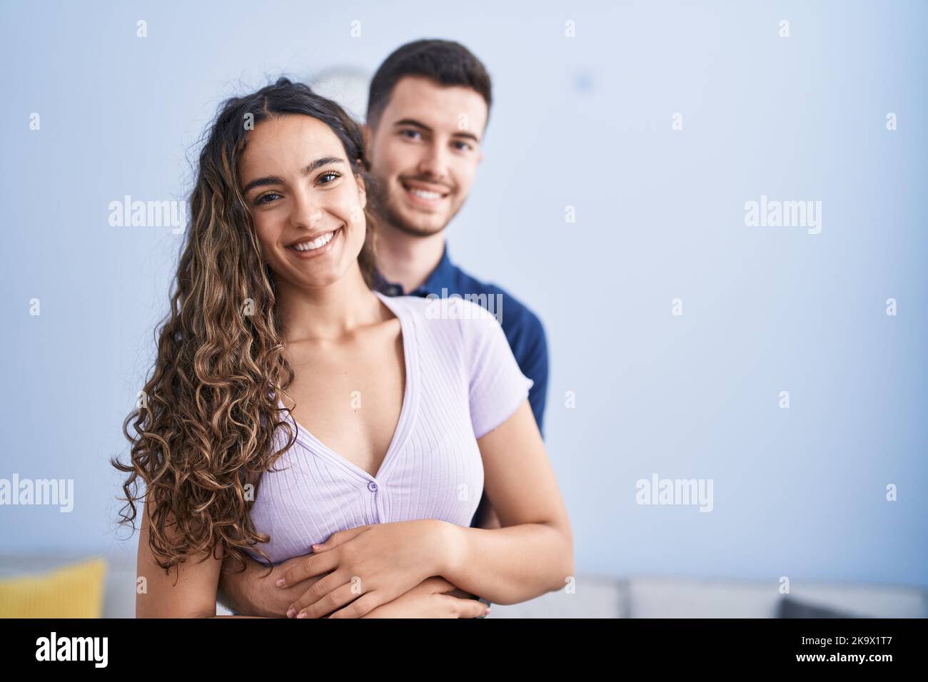 Young hispanic couple hugging each other standing at home Stock Photo ...