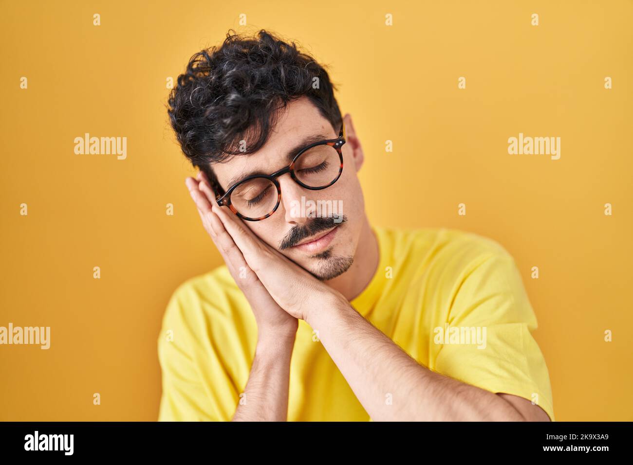 Hispanic Man Wearing Glasses Standing Over Yellow Background Sleeping 